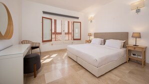 Een slaapkamer met een bed, nachtkastjes, een bureau, een stoel en een raam met luiken.