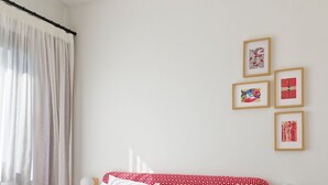 A neatly made bed with white and red bedding, a small round table, and wall-mounted light fixtures. - Vesta - Luxury APT - 2BR - Kamaran (El Gouna)