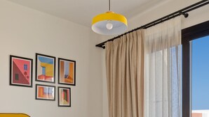 A neatly made bed with white linens and towels, a yellow headboard, and a large window with a view of buildings. - Vesta - Luxury APT - 2BR - Kamaran (El Gouna)