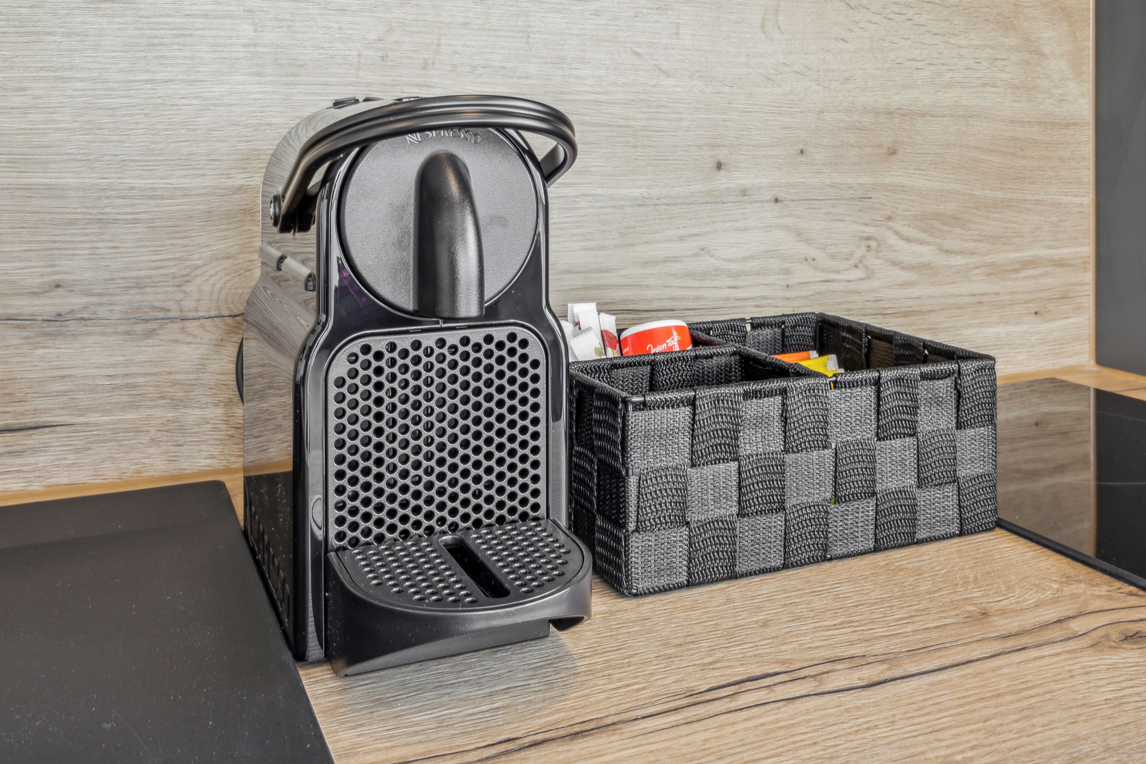 A coffee machine and a storage basket on a wooden surface.