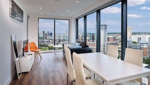 A modern room with a large window, a dining table, and a sofa. - Quayside Penthouse w/ City Views & Fast WiFi (Greater Manchester)