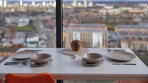 A dining table with plates, bowls, and cutlery, set against a city view. - Quayside Penthouse w/ City Views & Fast WiFi (Greater Manchester)