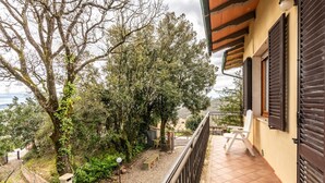 A balcony with a view of trees and a building. - Apartment 'Casa Vacanza Montecapino' in the Tuscan Hills (Chiusdino)