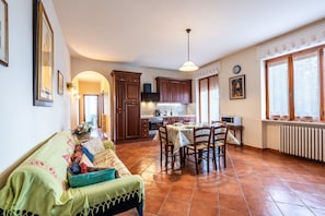 Amplia sala de estar con sofá, mesa de comedor y cocina al fondo.
