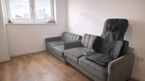 Ein graues Sofa in einem Zimmer mit Fenster, Heizkörper und Blick auf Gebäude.