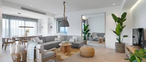 Ein geräumiges Wohnzimmer mit grauem Sofa, Holztisch und großem Spiegel.