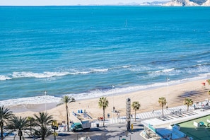 A beachside view with a road, palm trees, and a building named "Roman." - Rincón 12-B Apartment, Levante Beach (Benidorm)