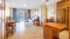 Een ruime woonkamer met een houten eettafel, een bank en een kitchenette.