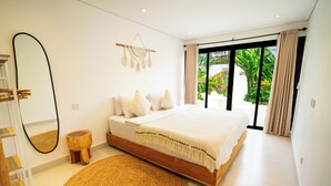 A modern bedroom with a large bed, a small wooden stool, a woven rug, and a large mirror. - Solla Sol Villa Canggu (Kerobokan)