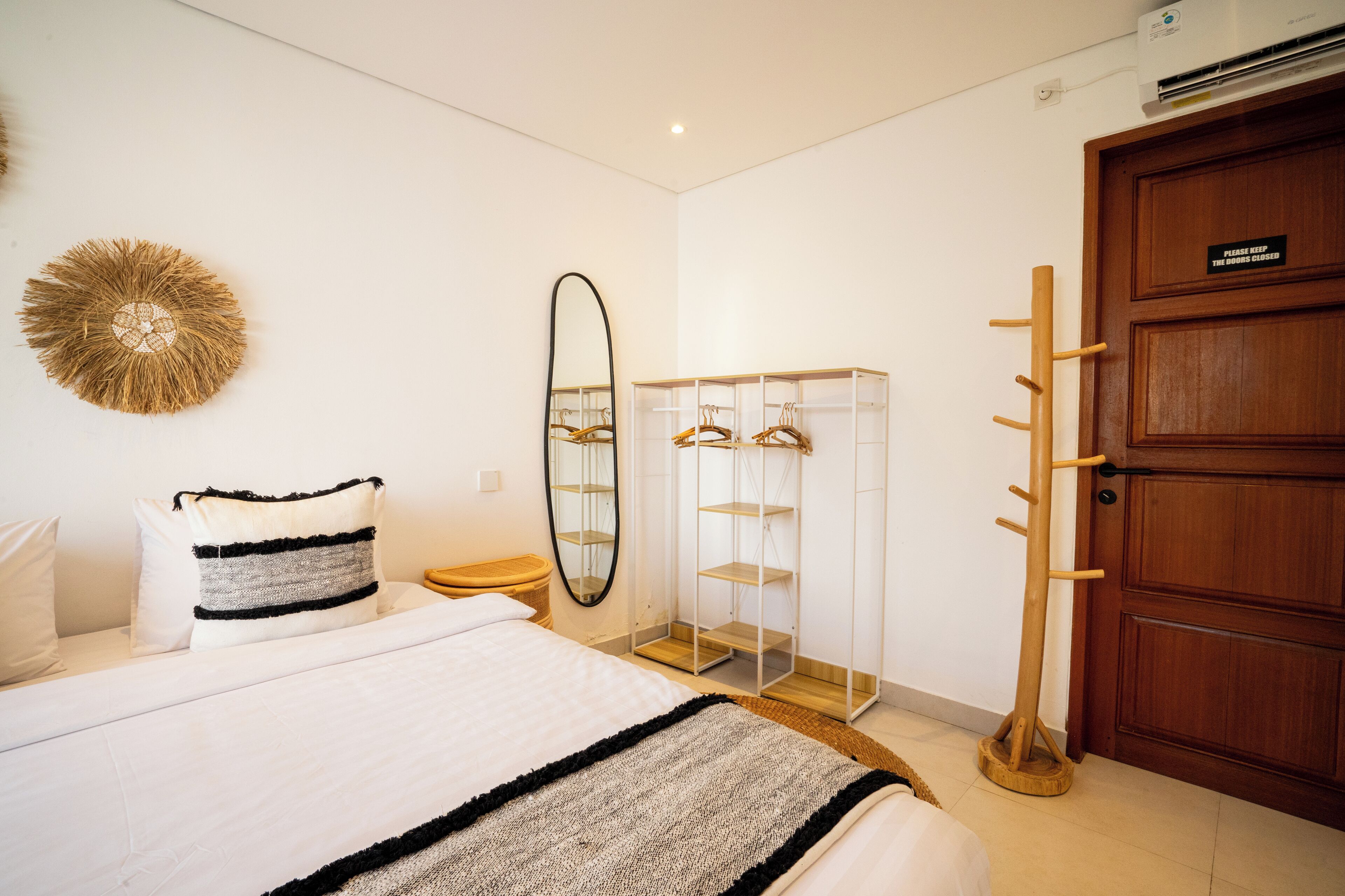 Ein Schlafzimmer mit Bett, Kleiderschrank, Spiegel und Kleiderhaken.