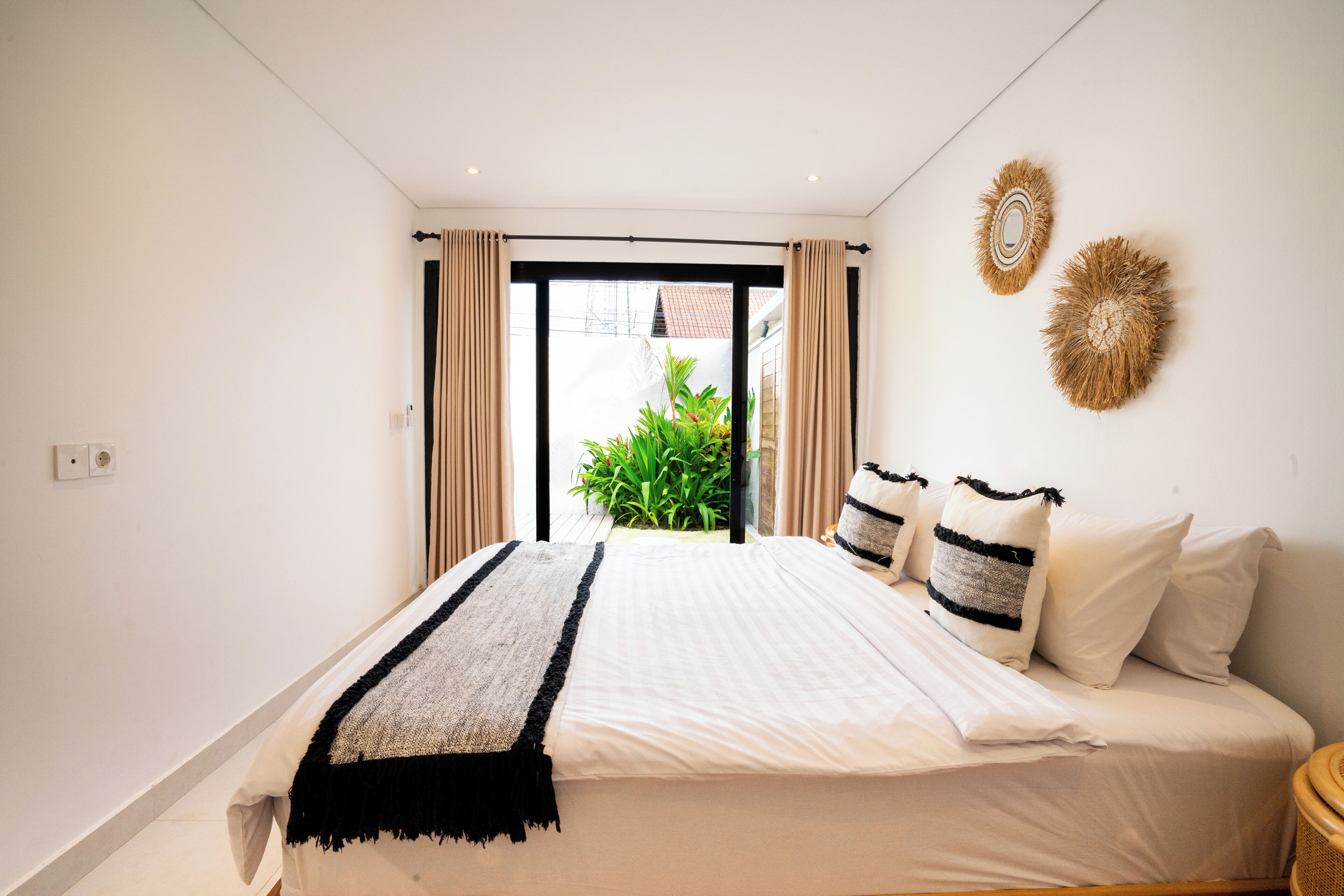 A bedroom with a bed, curtains, and a view of greenery outside.