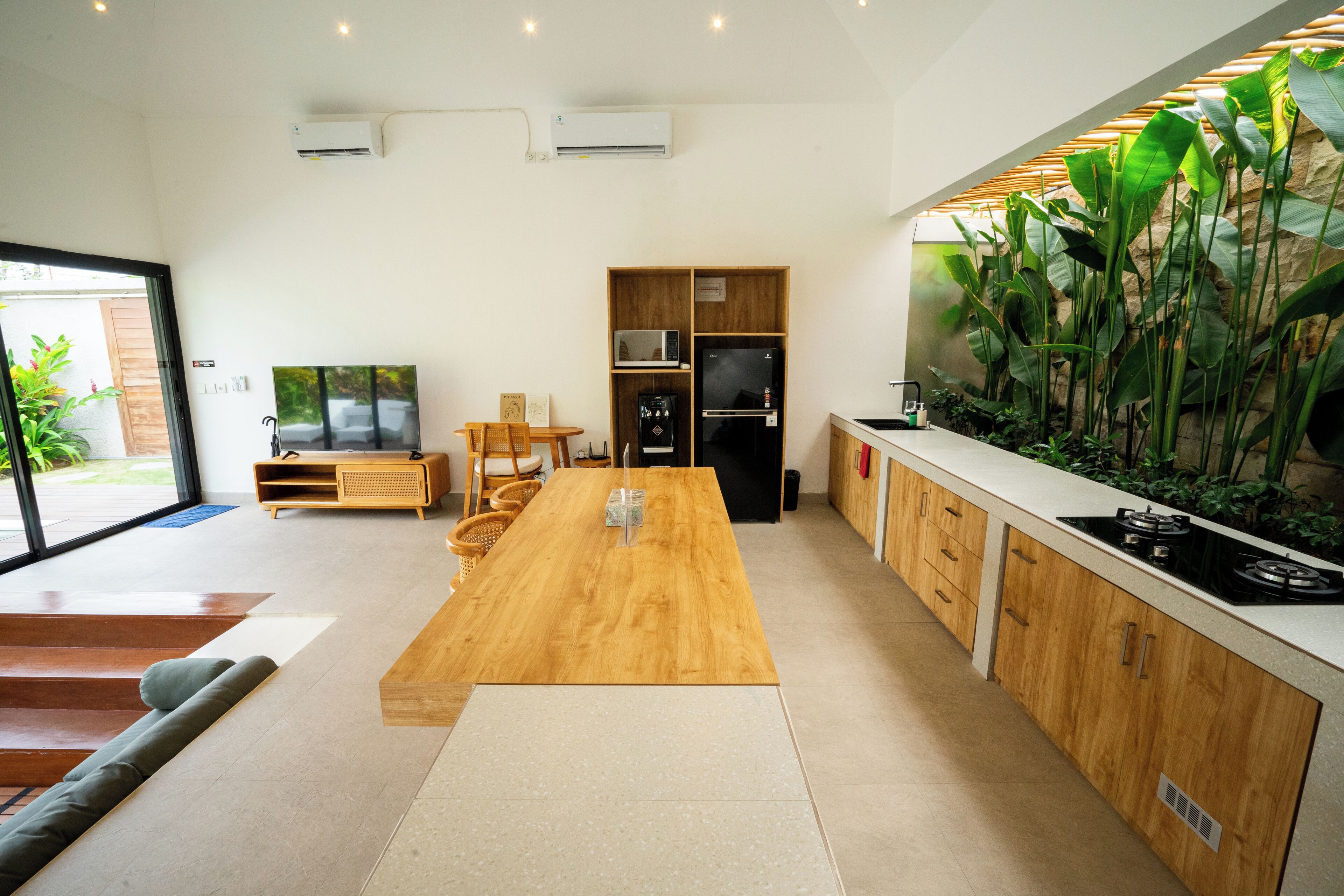 Una cucina moderna con isola in legno, elettrodomestici integrati e un'ampia finestra che si affaccia su un giardino.