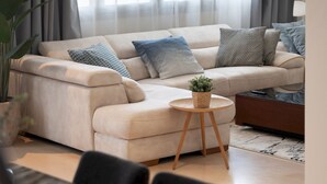 Una sala de estar moderna con un sofá color crema, una mesita redonda de madera y una mesa de centro.