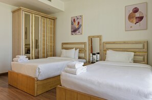 A hotel room with two beds, a wardrobe, and artwork on the walls. - Vesta - Luxury Apt- 3BR - Cfc Xli (New Cairo)