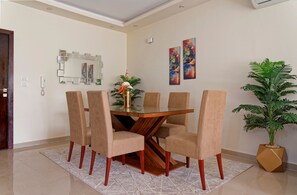 Ein Essbereich mit einem Glastisch, sechs Stühlen, einer Blumenvase und zwei Wandbildern.
