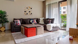 A modern living room with a sectional sofa, a coffee table, and a potted plant. - Vesta - Luxury APT - 2BR - La Mirada II (New Cairo)