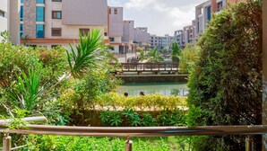 A view of a modern building complex with a bridge over a water feature, surrounded by greenery. - Vesta - Luxury APT - 2BR - La Mirada II (New Cairo)