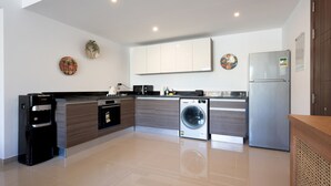 Una cocina moderna con lavadora integrada, refrigerador y dispensador de agua.