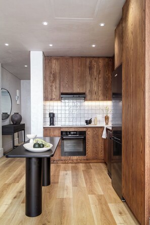Eine moderne Küche mit Holzschränken, einem schwarzen Kühlschrank und einer gefliesten Spritzschutzwand.