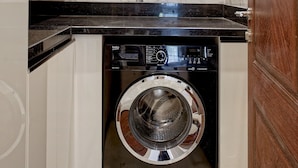 Un espace buanderie compact comprenant un lave-linge, un mur recouvert de carreaux de marbre et un ventilateur de plafond.