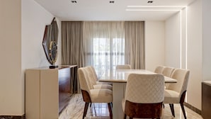 Une salle à manger moderne avec un sol en marbre, une grande table et six chaises rembourrées.