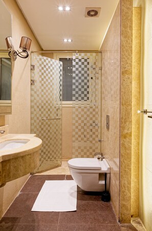 Ein Badezimmer mit Duschkabine mit Schachbrettmuster, Toilette und Waschbecken.