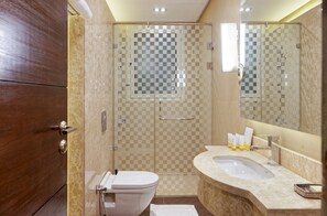 Ein modernes Badezimmer mit einer Duschkabine aus Karoglas, einer weißen Toilette, einem Marmorwaschbecken und einem großen Spiegel.