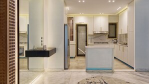 A modern kitchen with white cabinets, a marble countertop, and a built-in oven. - Vesta - Luxury APT - 1BR - Lake View Residence (New Cairo)