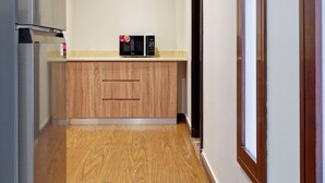 A narrow hallway with a wooden floor, a kitchen area with a microwave, and a refrigerator. - Vesta - Luxury APT - 2BR - New Cairo II (New Cairo)