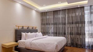 A modern bedroom with a bed, bedside table, and curtains. - Vesta - Luxury APT - 2BR - New Cairo II (New Cairo)
