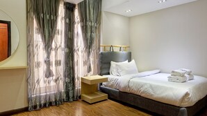 Un dormitorio moderno con cama, mesita de noche y cortinas.