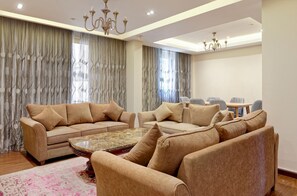 A spacious living room with a beige sofa set, a coffee table, and a chandelier. - Vesta - Luxury APT - 3BR - New Cairo V (New Cairo)