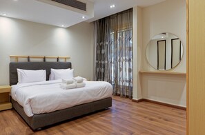 A neatly made bed with white linens and towels, a grey headboard, and a wooden nightstand. - Vesta - Luxury APT - 3BR - New Cairo V (New Cairo)