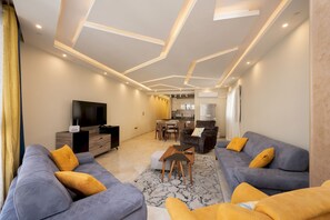 A modern living room with sofas, a coffee table, and a TV. - Vesta - Luxury APT - 2BR - Kattameya one (Cairo)