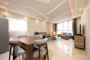 A modern living room with a wooden dining table, two sofas, and a TV. - Vesta - Luxury APT - 2BR - Kattameya one (Cairo)