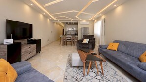 A modern living room with a flat-screen TV, sofa, and coffee table. - Vesta - Luxury APT - 2BR - Kattameya one (Cairo)