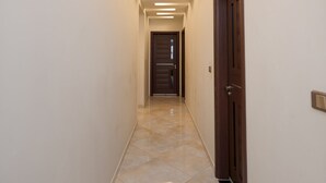 A hallway with a tiled floor, recessed lighting, and a wooden door at the end. - Vesta - Luxury APT - 2BR - Kattameya one (Cairo)