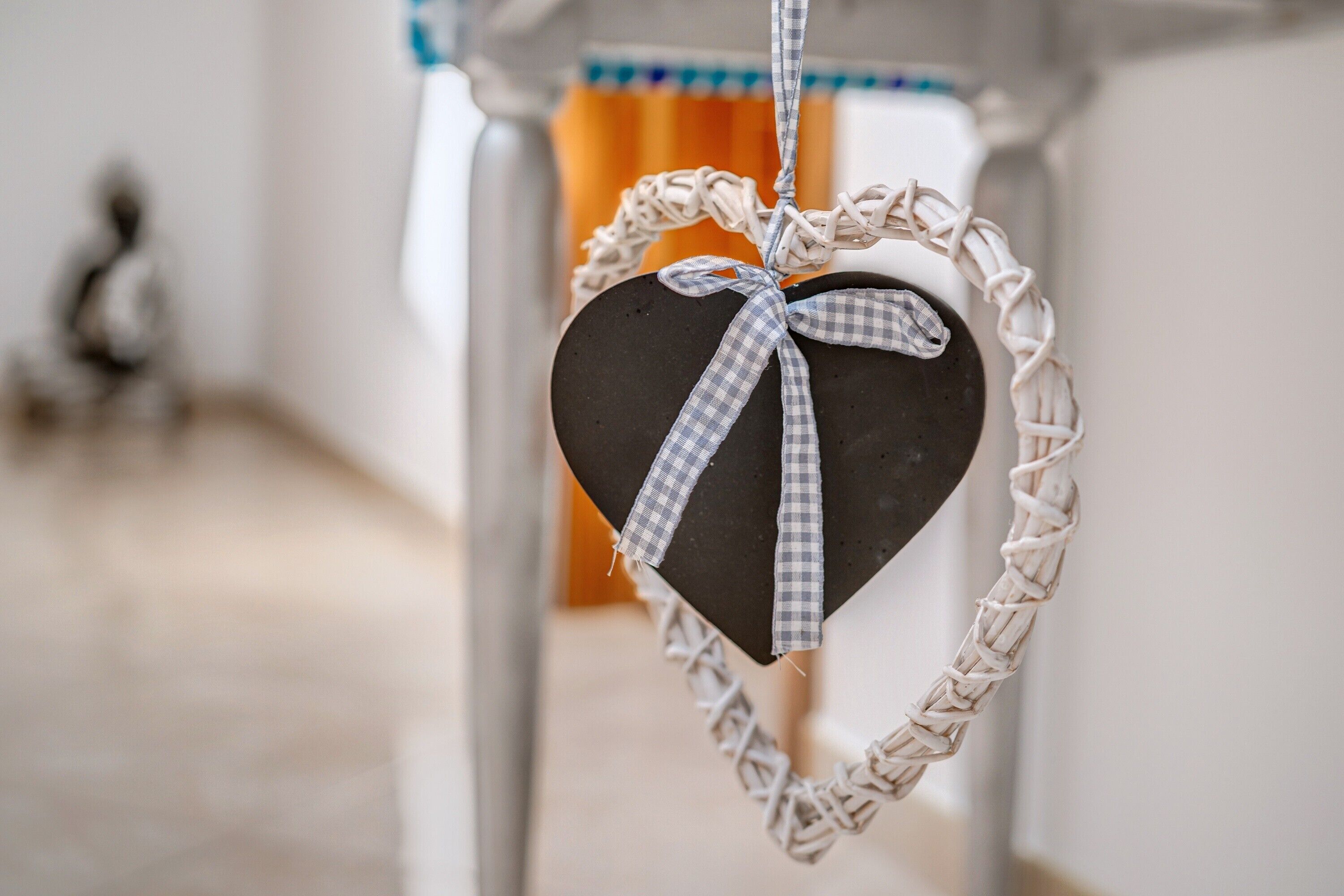 Una decoración con forma de corazón, con un lazo a cuadros y un borde trenzado, colgando de un accesorio del techo.