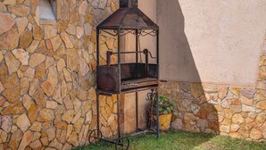 Un muro de piedra con una estructura de asador metálico al aire libre.