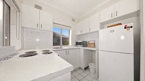 A modern kitchen with white cabinets, a gas stove, a microwave, and a refrigerator. - Metawise BnB 2BR Hillsdale Family Stay Sleeps 6 (Sydney)