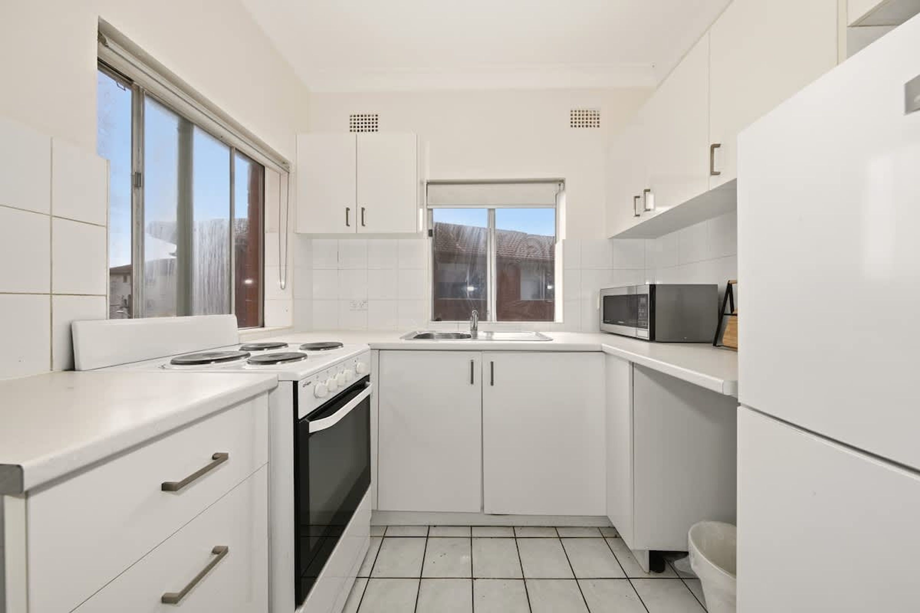 Een moderne keuken met witte kasten, een fornuis en een magnetron.
