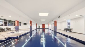 A swimming pool with clear lane markings, surrounded by white walls and red pillars, with seating areas on both sides. - Metawise BnB Bright Open 2BR Arncliffe Sleeps 6 (Sydney)