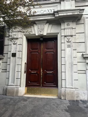 A double wooden door with a brass handle, flanked by stone columns and a decorative keystone. - Roma Elegante 3 Bedrooms With 5 Star Comfort in Stylish Prati Neighborhood (Rome)