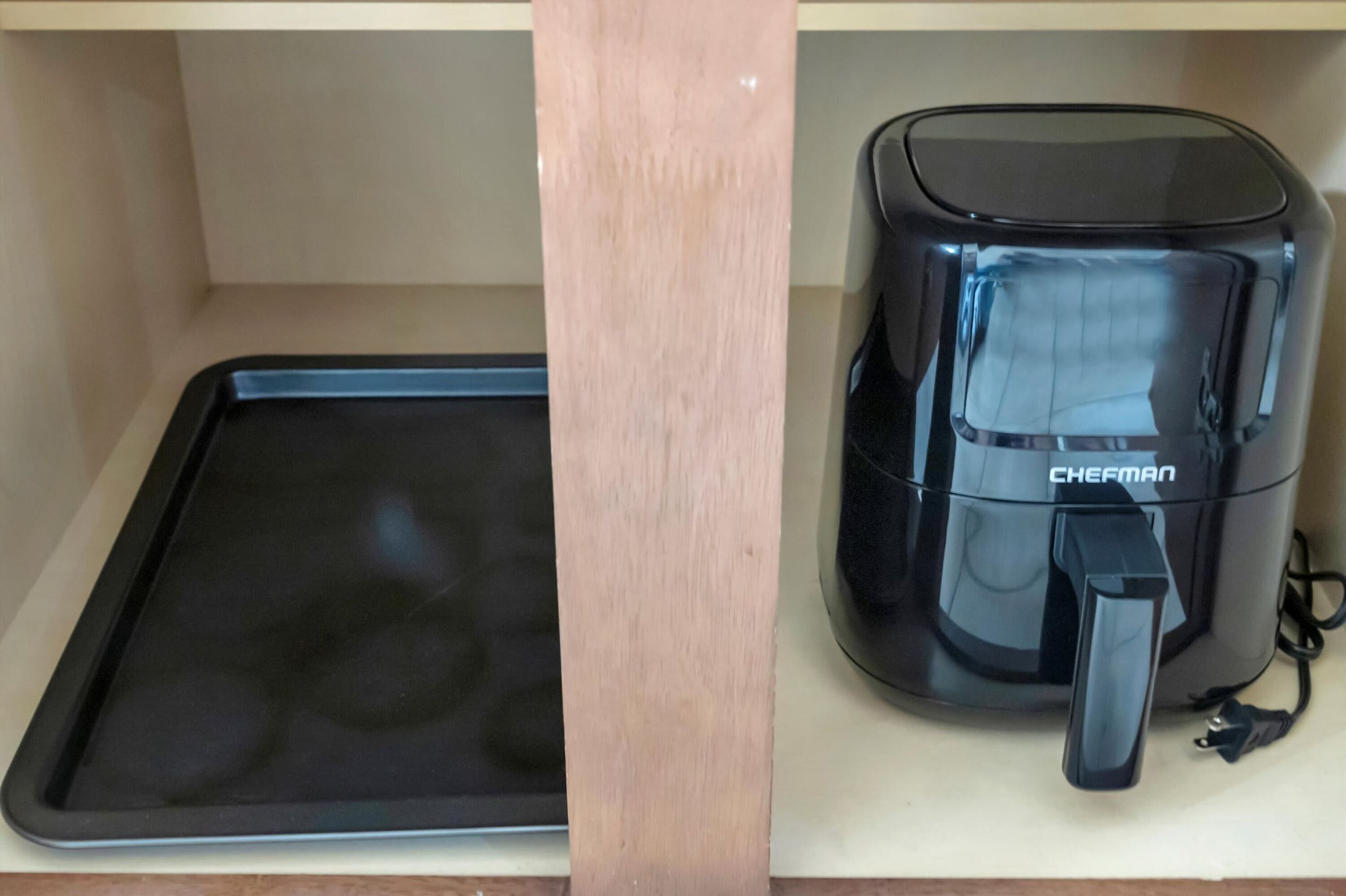 Ein schwarzer Wasserkocher und ein schwarzes Tablett auf einem Holzboden.