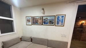 Una sala de estar con un sofá modular, una ventana y cuatro cuadros en la pared.