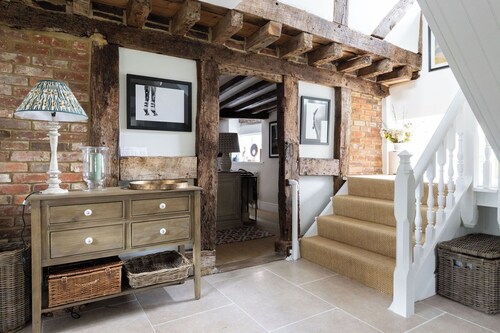 A charming Grade II listed holiday home in Petworth, recently remodelled with original beams, 3 bedrooms, 2 bathrooms a modern kitchen, cosy living space, and a large garden with pergola seating.