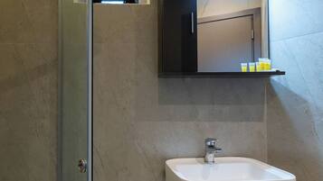 Ein modernes Badezimmer mit Duschkabine aus Glas, einem weißen Waschbecken und einem Spiegel darüber.
