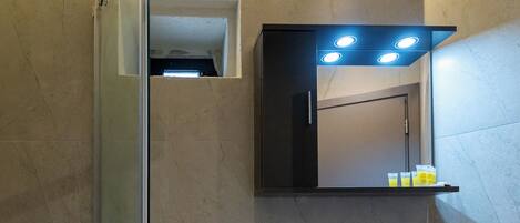 Un baño moderno con cabina de ducha de vidrio, un lavabo blanco y un espejo sobre el lavabo.