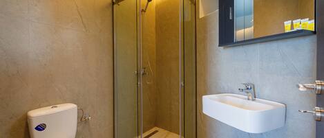 A modern bathroom with a glass-enclosed shower, a white sink, and a marble-tiled floor.