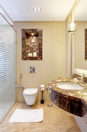 Ein modernes Badezimmer mit integriertem Bidet, zwei Waschbecken, einem Marmor-Waschtisch und einem wandmontierten Spiegel.
